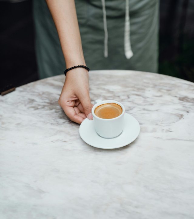 Crop barista serving cup of coffee