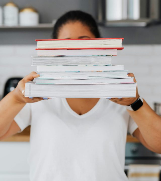Woman Holding a Pile of Books in Her Hands 